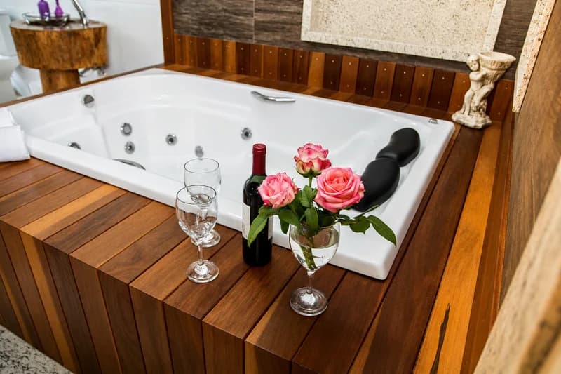 Banheira de hidromassagem da Suíte Araucária, posta com taças, vinho e flores