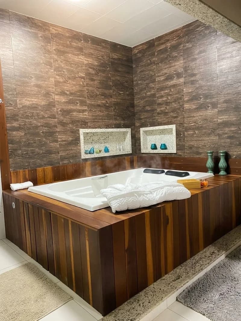 Banheira de hidromassagem da Suíte Araucária, revestida de madeira, com toalhas na borda