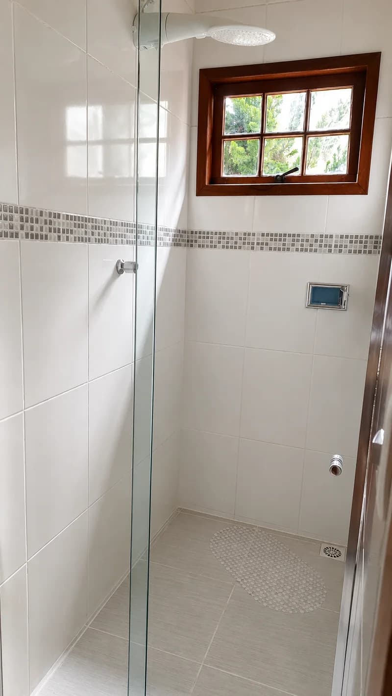 Banheiro da Suíte Cascata, com box de vidro e janela de madeira