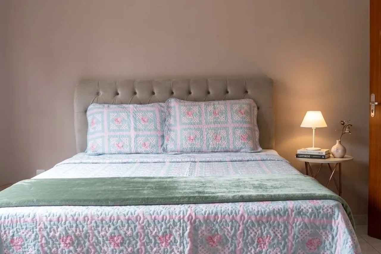 Double bed in the Hortênsias Suite, with a patterned bedspread and a bedside lamp