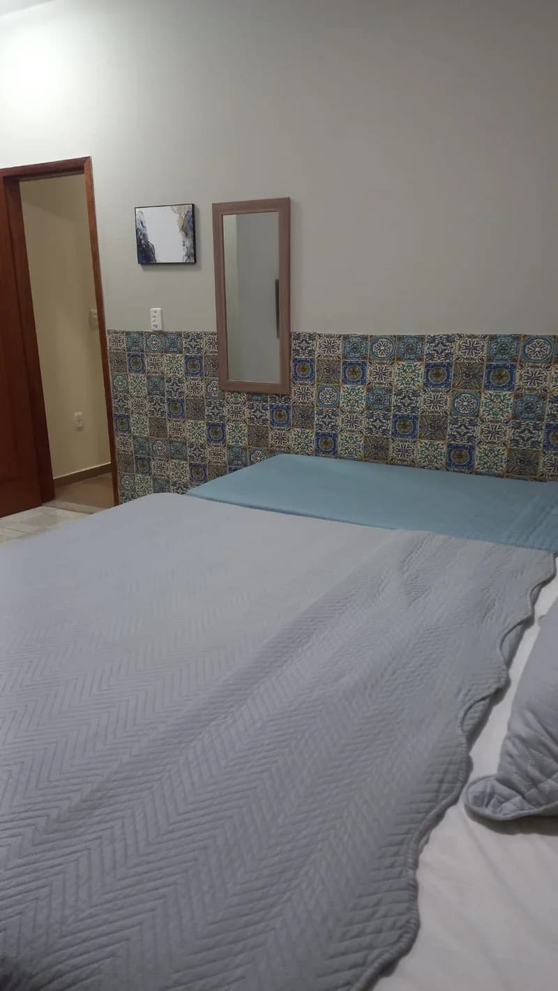 Quarto da Suíte Manacá, com cama de casal e faixa de azulejos coloridos na parede